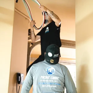 Solar installers routing electrical wiring through conduit in a residential garage