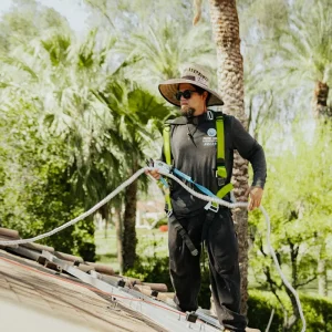 Solar technician positioning a safety line on a residential rooftop during installation