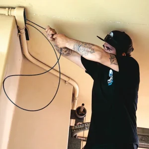 Solar technician pulling cable through conduit during residential solar installation