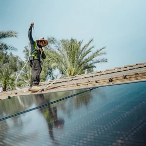 Solar technician working beside installed solar panels on a residential rooftop