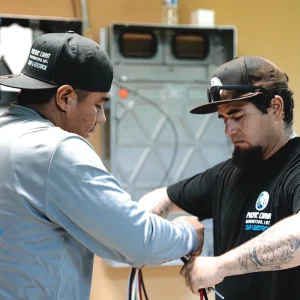 Two solar technicians connecting electrical wiring during a residential solar installation